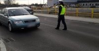 zdjęcie kolorowe, na którym widać funkcjonariusza Wydziału Ruchu Drogowego podchodzącego do zatrzymanego auta w celu zbadania stanu trzeźwości kierującego.