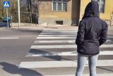 Na zdjęciu osoba piesza stojąca przy pasach i oczekująca na możliwość wejścia na jezdnię.