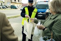 Na fotografii policjant rozdają torby odblaskowe