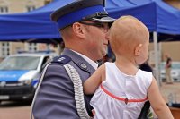 Święto Policji Łomża - uroczysty apel. Na zdjęciu funkcjonariusz z dzieckiem.