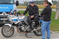 Policjant siedzący na motocyklu służbowym rozmawia z młodym mężczyzną