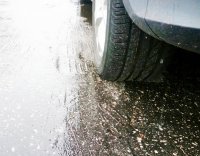 Zdjęcie ilustracyjne - koło samochodu na mokrej nawierzchni jezdni.