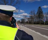 Policjant z fotoradarem skierowany w kierunku drogi