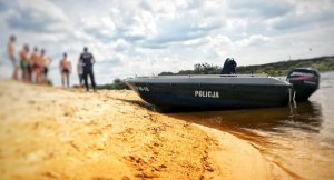 policyjna łódka i policjant rozmawiający z plażowiczami