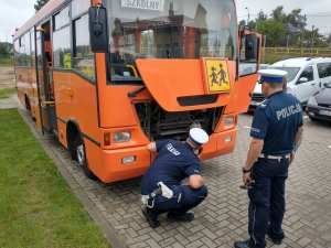 policjanci sprawdzający stan techniczny autobusu