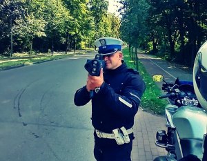 Policjant dokonujący pomiarów prędkości, laserowym miernikiem prędkości