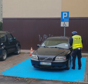 Policjant sprawdzający kartę parkingową w zaparkowanym pojeździe