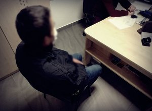 Mężczyzna w trakcie przesłuchania siedzący przy biurku