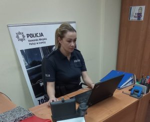 Policjantka siedząca przy biurku, pracująca na komputerze.