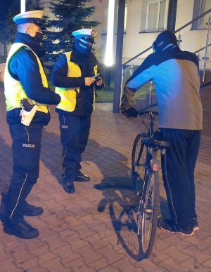 Dwóch policjantów rozmawia z mężczyzną trzymającym rower.
