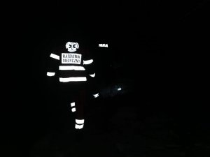 Zdjęcie wykonane w nocy, jest bardzo ciemno, jedyne co widać to napis policja i ratownik medyczny na ubraniach służbowych.