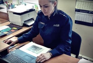 Policjantka siedząca przy biurku. Przed sobą ma otwarty laptop.