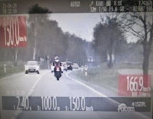 Zrzut ekranu z wideorejestratora. Na ekranie motocyklista po lewej stronie napis 150 kilometrów na godzinę