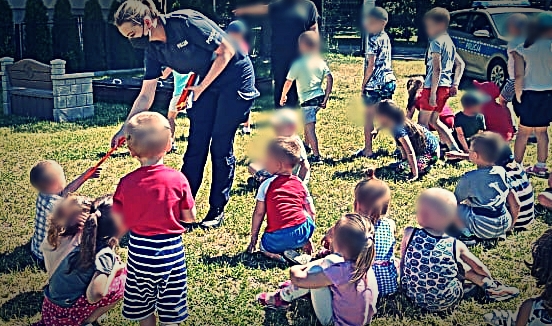 Policjantka rozdająca elementy odblaskowe podczas spotkania z dziećmi