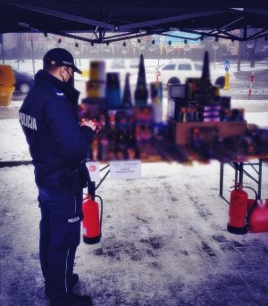 Policjant stojący przy stoisku z petardami i fajerwerkami