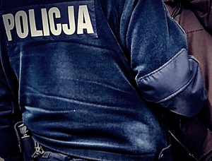 Policjant odwrócony plecami. Widać napis POLICJA na niebieskim polarze.