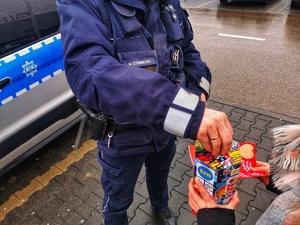 Policjant wrzuca pieniądze do puszki Wielkiej Orkiestry Świątecznej Pomocy.