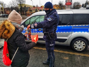Policjant wrzuca pieniądze do puszki Wielkiej Orkiestry Świątecznej Pomocy.