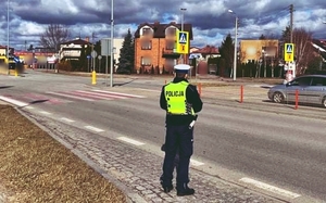 Policjant ruchu drogowego mierzy prędkość ręcznym miernikiem prędkości