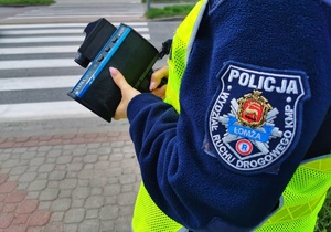 Policjantka trzyma w ręku ręczny miernik prędkości.