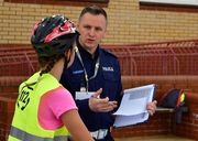 Umundurowany policjant rozmawia z dziewczynką na rowerze