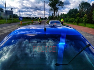 Dwóch policjantów w trakcie kontroli samochodu osobowego.