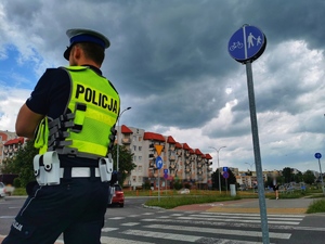 Policjant stojący przy przejściu dla pieszych i ścieżki dla rowerów