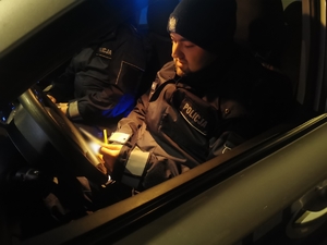 Policjant siedzi w radiowozie. Panuje noc
