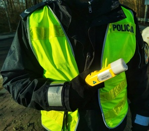 Policjant trzyma w ręku urządzenie do badania stanu trzeźwości