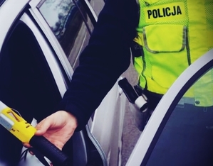 Policjant przeprowadza kontrolę trzeźwości u zatrzymanego kierowcy