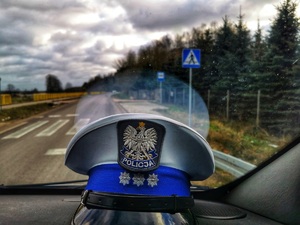 Policyjna czapka i w tle znak drogowy