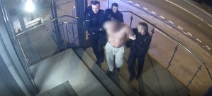 Mężczyznę bez koszulki, który ma założone kajdanki na ręce trzymane z tyłu prowadzą policjanci schodami do Komendy Miejskiej Policji w Łomży.