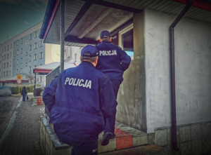 Dwóch policjantów wchodzi do klatki schodowej bloku