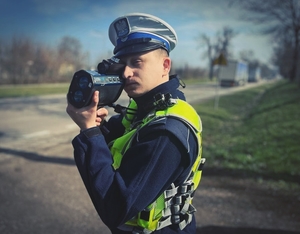 policjant mierzący prędkość ręcznym miernikiem prędkości