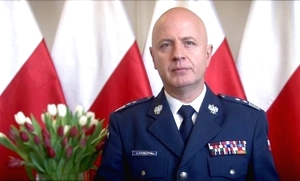 Komendant Główny Policji na tle flag biało- czerwonych
