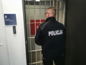 Policjant przed drzwiami aresztu